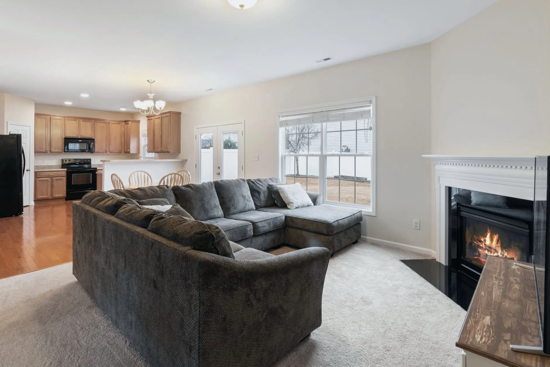 A carpeted family room with a sectional sofa and a fireplace
