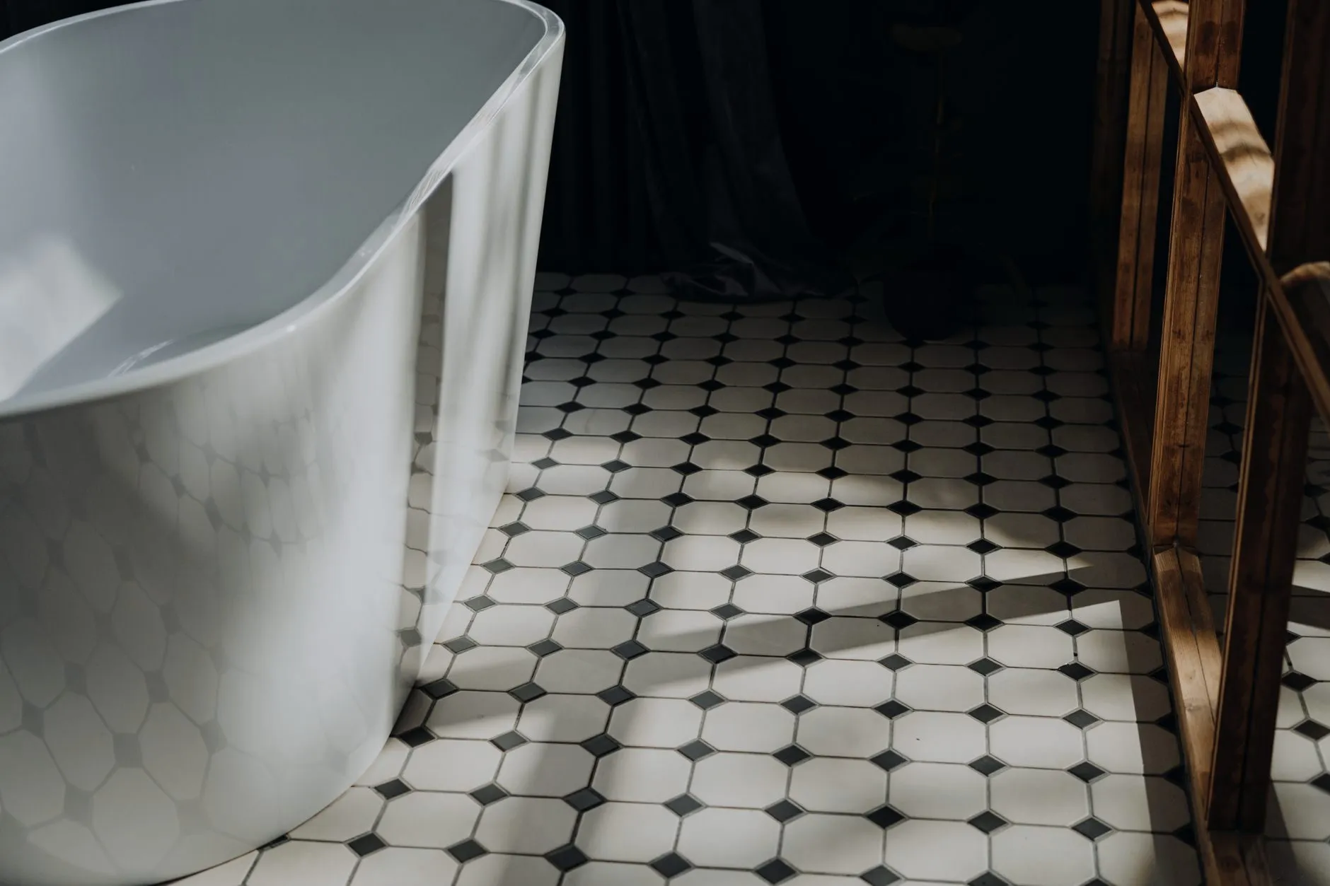 A black-and-white tile floor beside a white bathtub