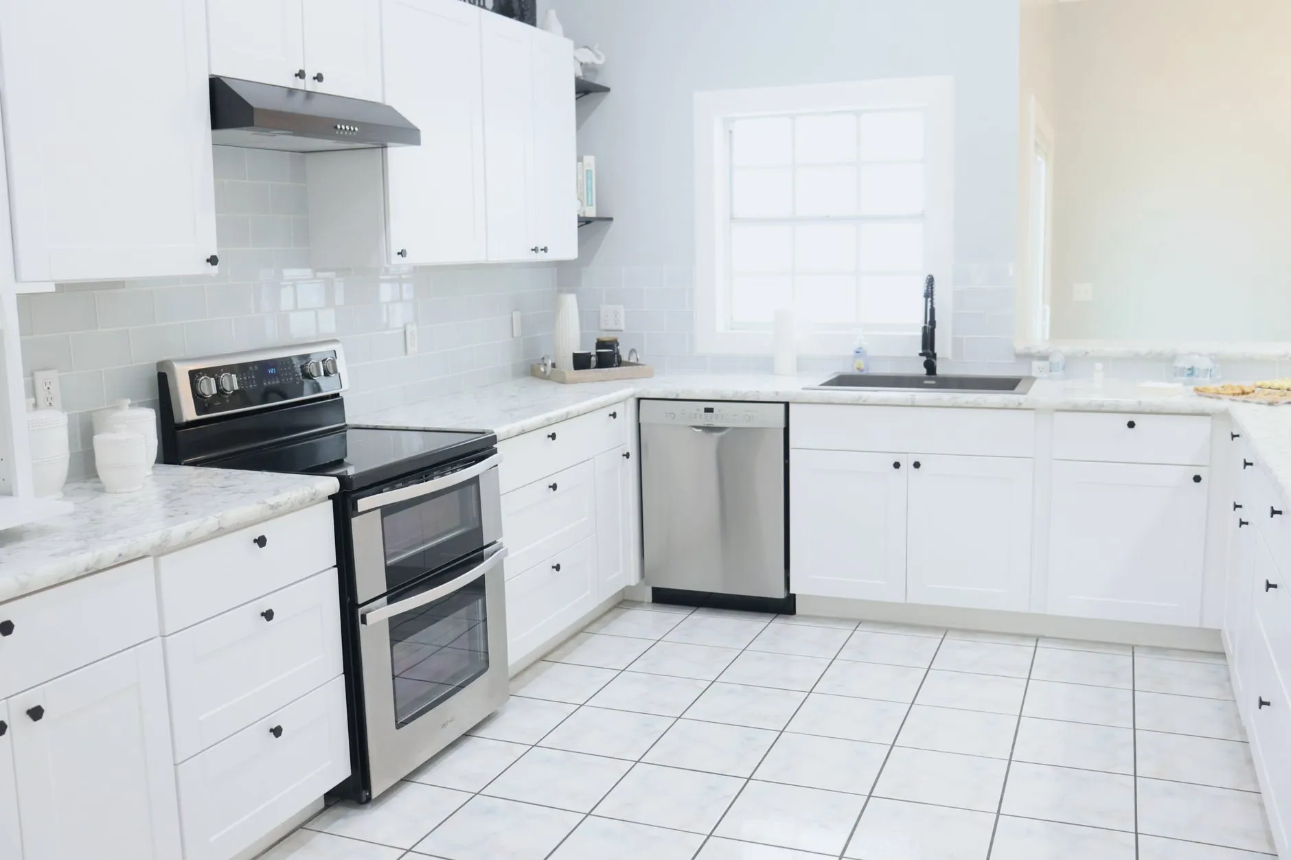 A bright kitchen with a white tile floor and grout lines
