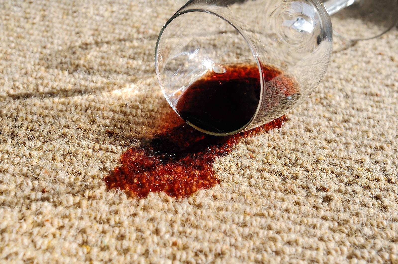 A glass of red wine spilt on a pure wool carpet.
