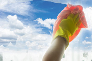 A gloved hand wiping a window against a blue sky