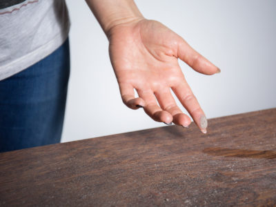 woman rubbing her finger through dust before she begins fall cleaning