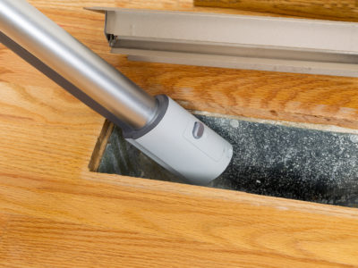 image of a person vacuuming an air duct