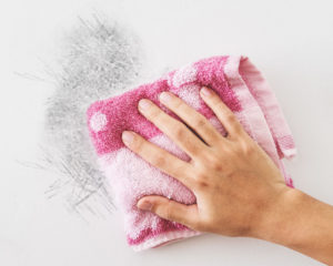 image of a hand cleaning a dirty wall