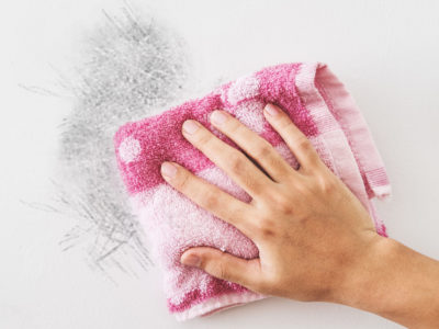 image of a hand cleaning a dirty wall